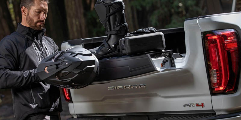 Man load some accessories in to GMC Sierra 2500HD's trunk